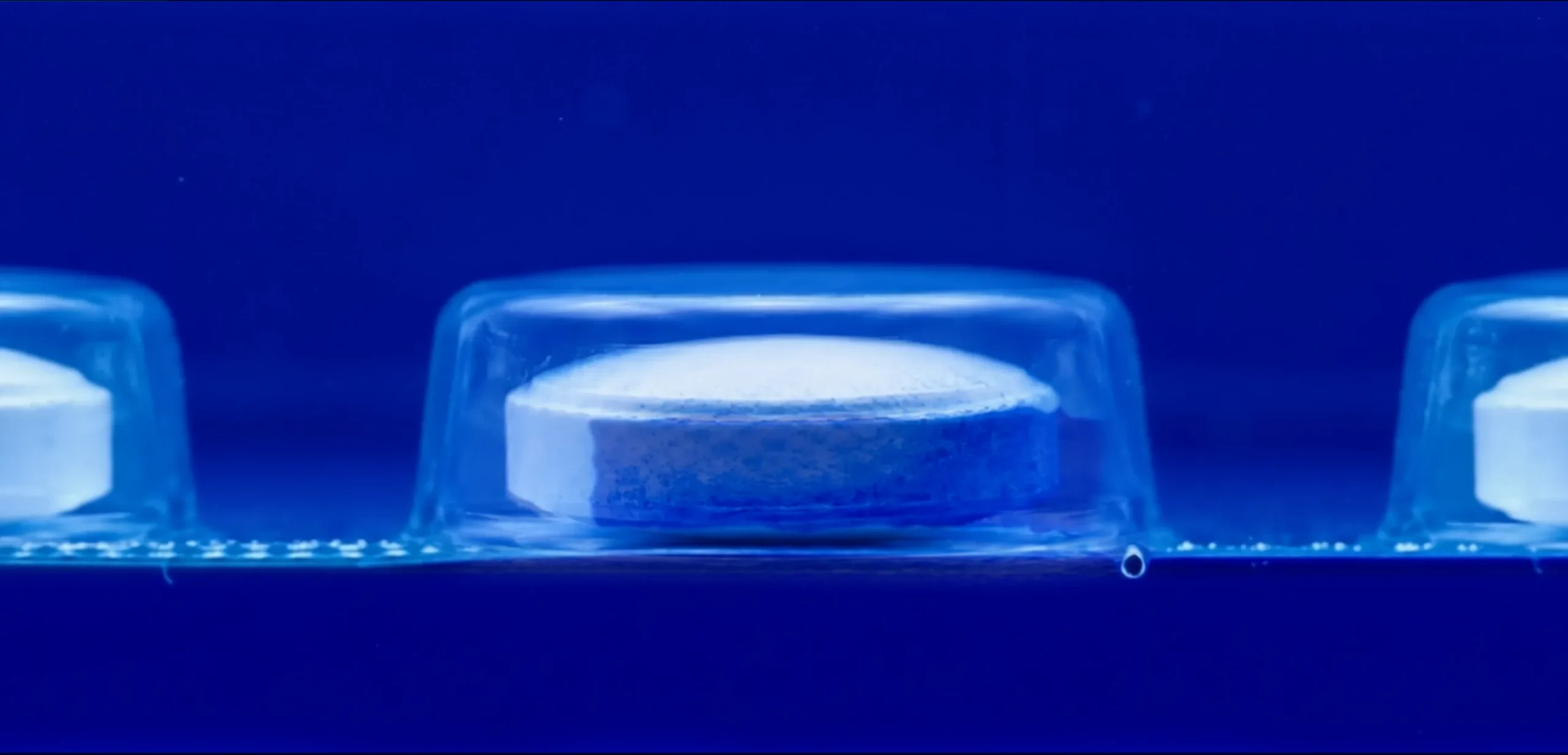 Detalhe do teste com corante mostrando solução de azul de metileno manchando comprimido farmacêutico